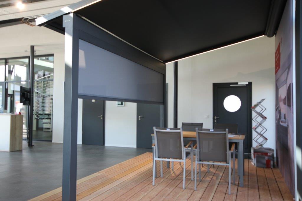 Pergola Markise in Grau im Ausstellungsraum des Betriebs von Metallbau Klement. Unter der Markise steht eine Tischgarnitur, Aufnahme von der Seite
