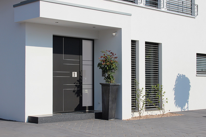 Moderne dunkle Eingangstür mit einem großen Blumentopf auf der rechten Seite