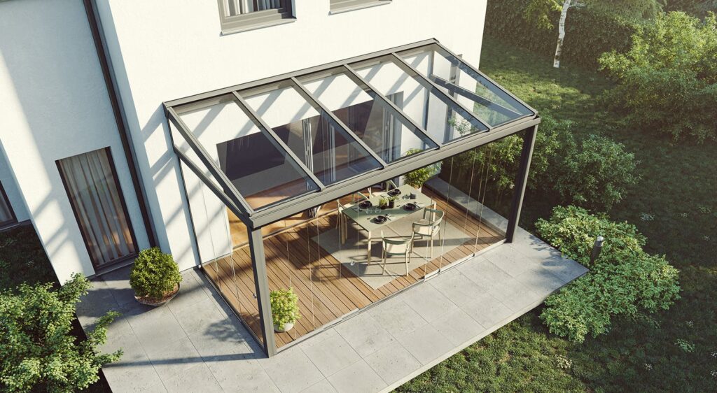 Moderner Wintergarten mit Glasdach und Glaswänden an einem weißen Haus, mit Esstisch und Stühlen auf Holzterrasse