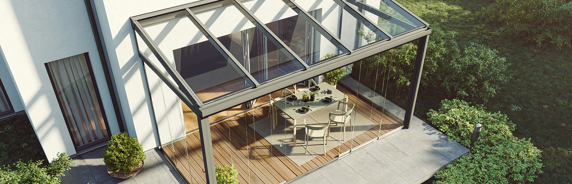 Terrassendach mit Glasdach und Glaswänden an einem modernen Einfamilienhaus, darunter Esstisch mit Stühlen auf Holzterrasse
