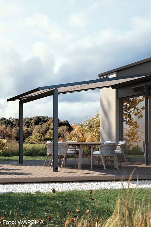 Terrasse mit modernem, ausfahrbarem WAREMA-Markisendach über einem Esstisch mit sechs Stühlen vor einem Haus mit großen Fenstern