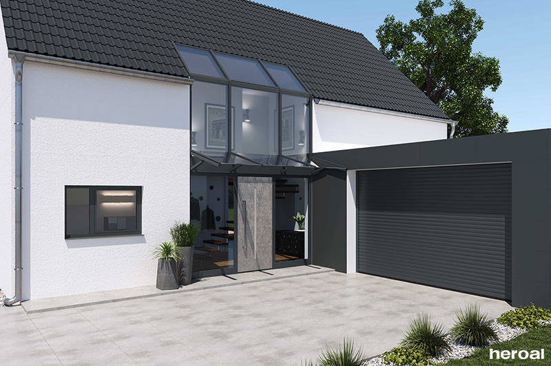Moderner Hauseingang mit großer Glastür, Vordach und angrenzender Garage mit dunklem Rolltor