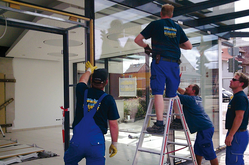 Das Montageteam von Metallbau Klement montieren eine Glasfassade an einem Laden