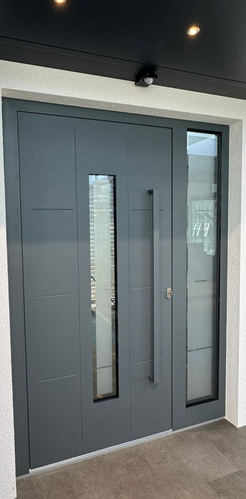 Moderne Haustür in Dunkelgrau mit langem vertikalem Fenster und seitlichem Glasstreifen